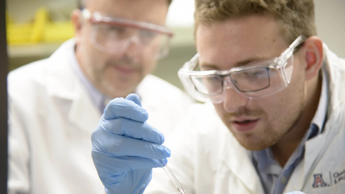 Chris Foley, PhD, right, is a postdoctoral researcher in the Hulme Lab, which is devoted to finding ways to nip Alzheimer’s disease in the bud by targeting an enzyme crucial to its development. Chris Hulme, PhD, is pictured in the background.