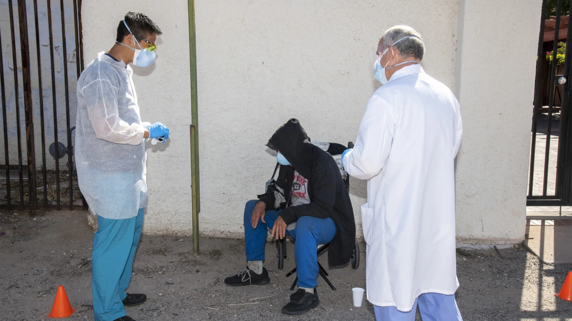 Medical student Christian Bergman (left) and Z Mansion owner Tom Hill (right) speak with an individual at Tucson’s Z Mansion downtown soup kitchen. Bergman and other medical students are helping provide health care services to this vulnerable population.