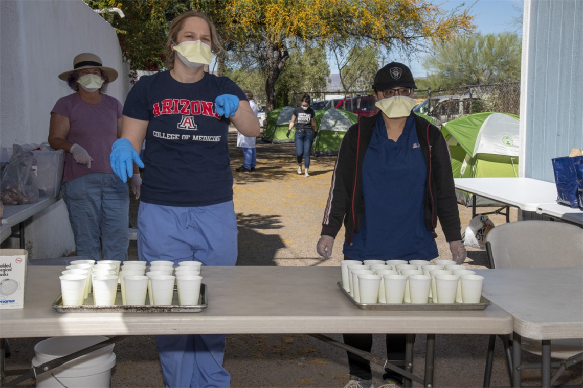College of Medicine – Tucson students Erika Krall and Dori Lin pour drinks to serve to homeless people during an outreach program to provide medical care to the vulnerable homeless population.