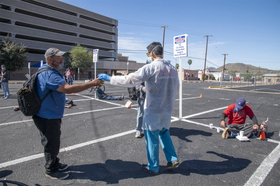 Christian Bergman hands out beverages at Tucson’s Z Mansion soup kitchen. He and other medical students are volunteering to provide health care services to the vulnerable homeless population.