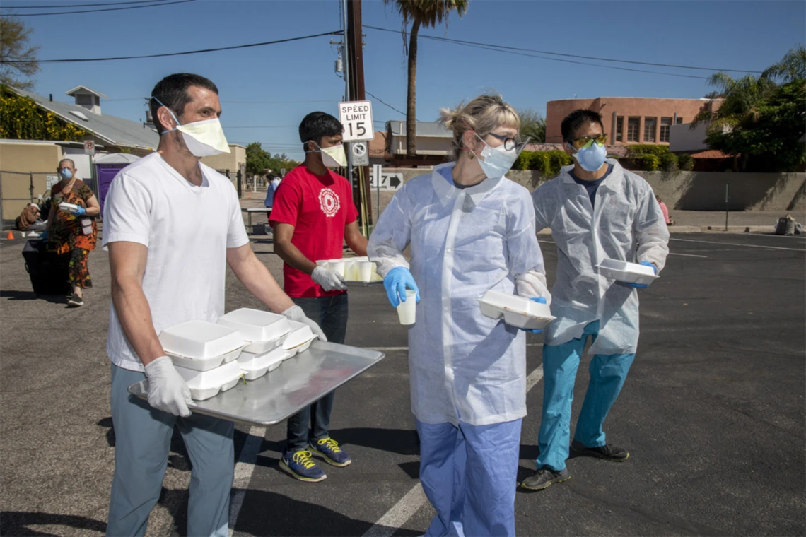 Medical students Jaime Contreras, Shrey Goel and Christian Bergman prepare to distribute food and drinks to homeless residents in Tucson who visit the Z Mansion soup kitchen. The students are also offering a medical clinic to help the vulnerable population during the global pandemic of COVID-19.