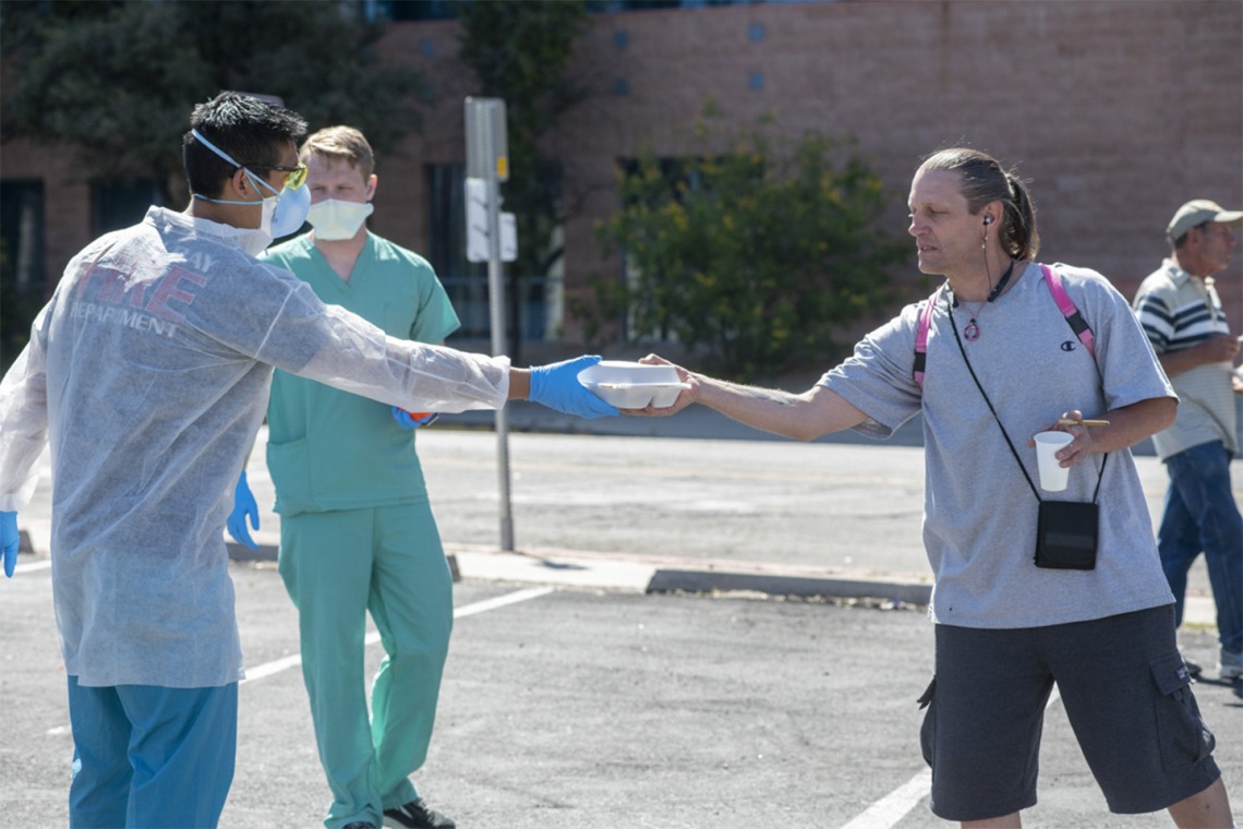 Medical students Christian Bergman and Chris Vance try to keep a safe distance to protect the homeless population they serve during the Commitment to Underserved People’s clinic at a soup kitchen in downtown Tucson.