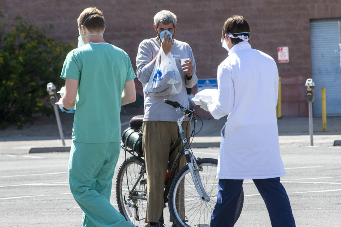 Chris Vance (right) and another College of Medicine – Tucson student offer food, drinks and medical services to the homeless population served at Z Mansion several times a week.