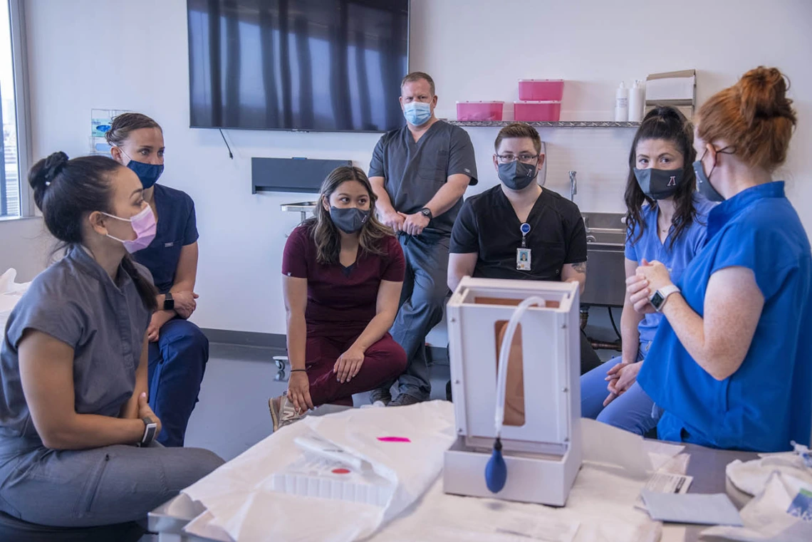 Courtney Bartlett, DNP, AGACNP, instructs students on thoracentesis/paracentesis. 