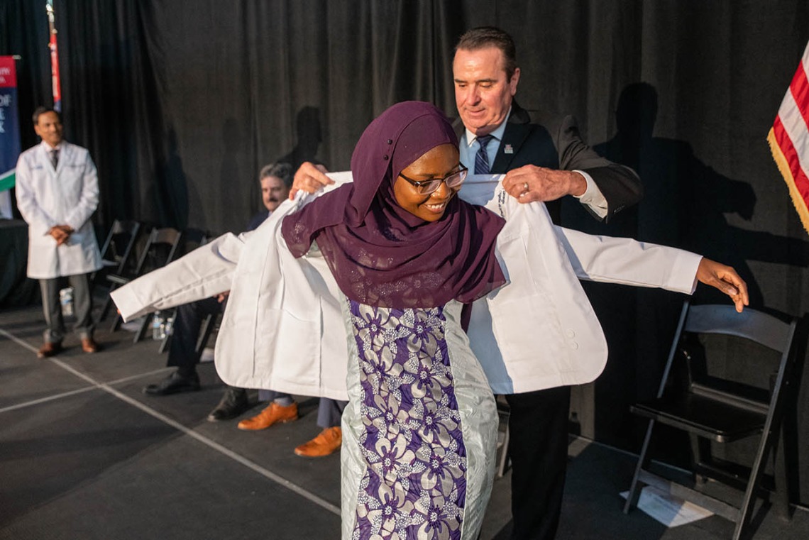 Fatouma Tall receives her white coat from Paul Standley, MD.
