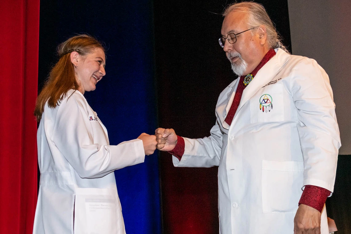 Jordan Gotwalt gets a fist bump from Dr. Carlos Gonzales after he presented her with her white coat. 