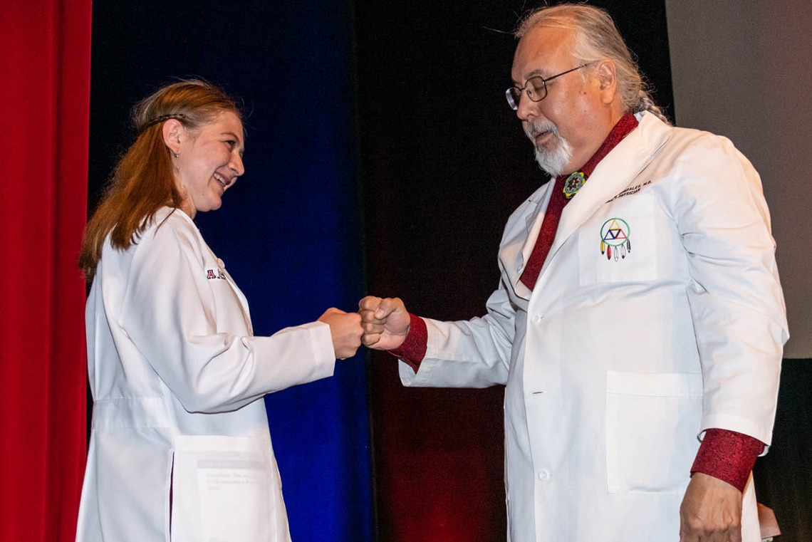 Jordan Gotwalt gets a fist bump from Dr. Carlos Gonzales after he presented her with her white coat. 