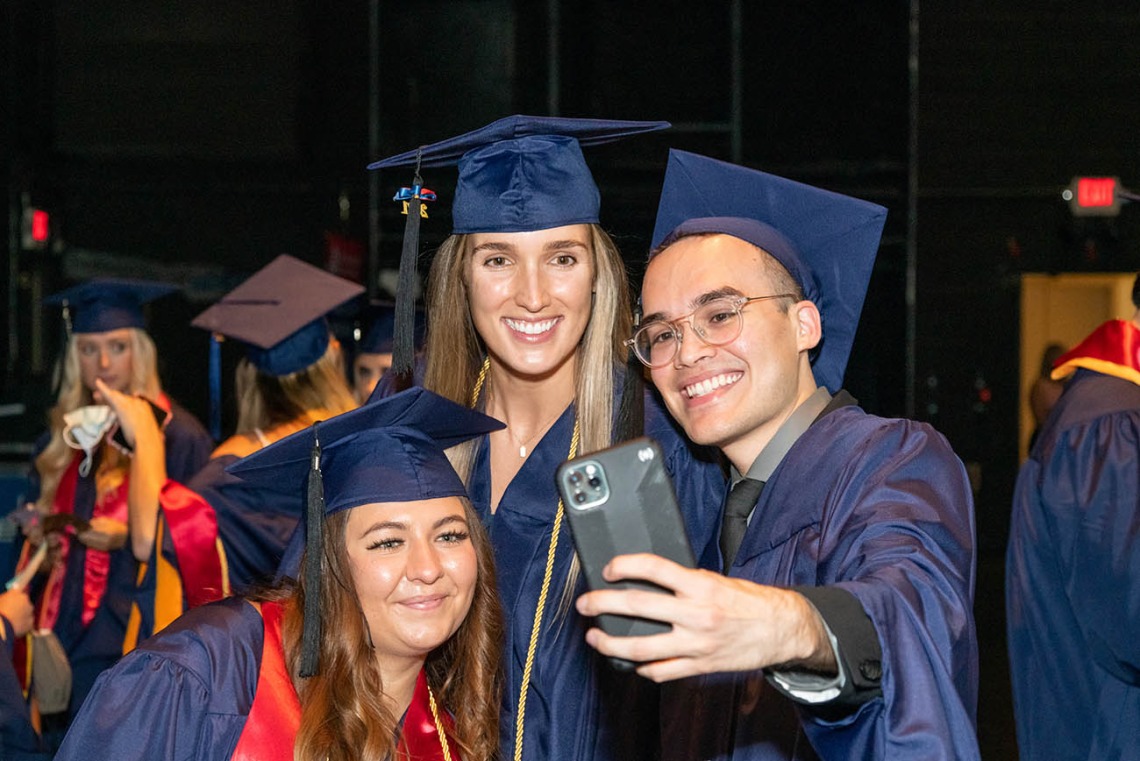 From left, Ivana Matovic, Allison Gilbert and Aaron Gomez take a selfie before the start of the August commencement ceremony at Centennial Hall.