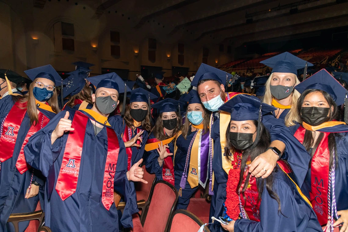 Graduates pose after commencement at Centennial Hall.