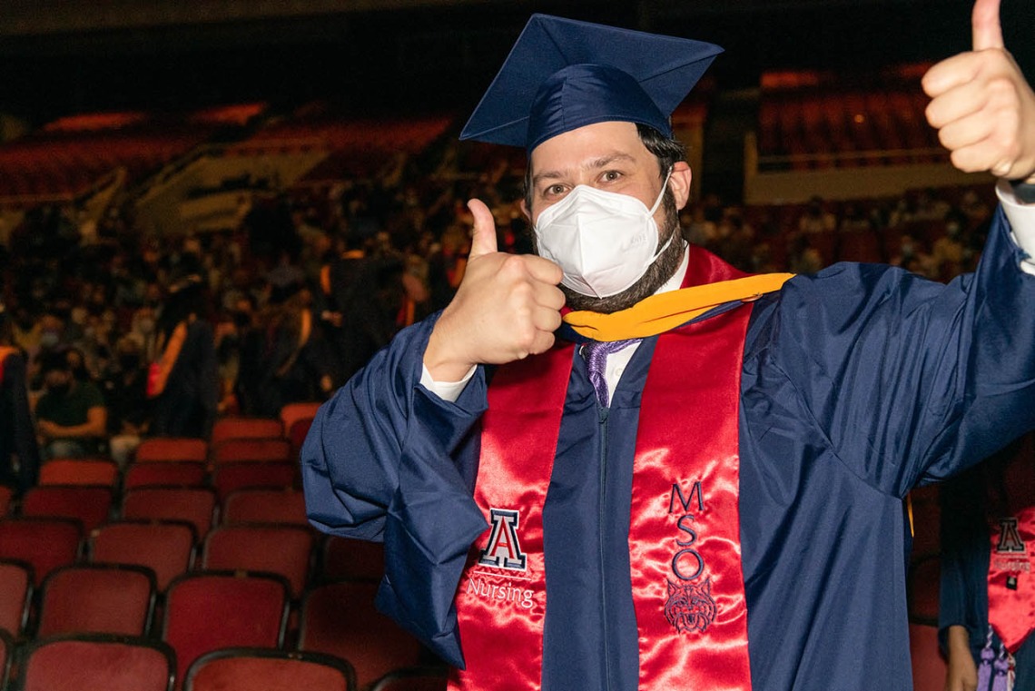 A graduate gives the thumbs up as he exits after the August commencement at Centennial Hall.