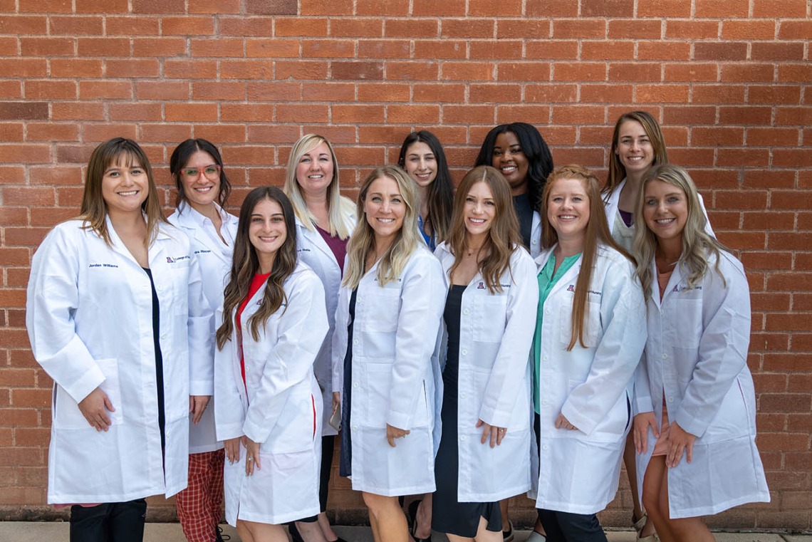 A group of Doctor of Nursing Practice students who received their white coats during the ceremony pause for a photo outside of Crowder Hall. 