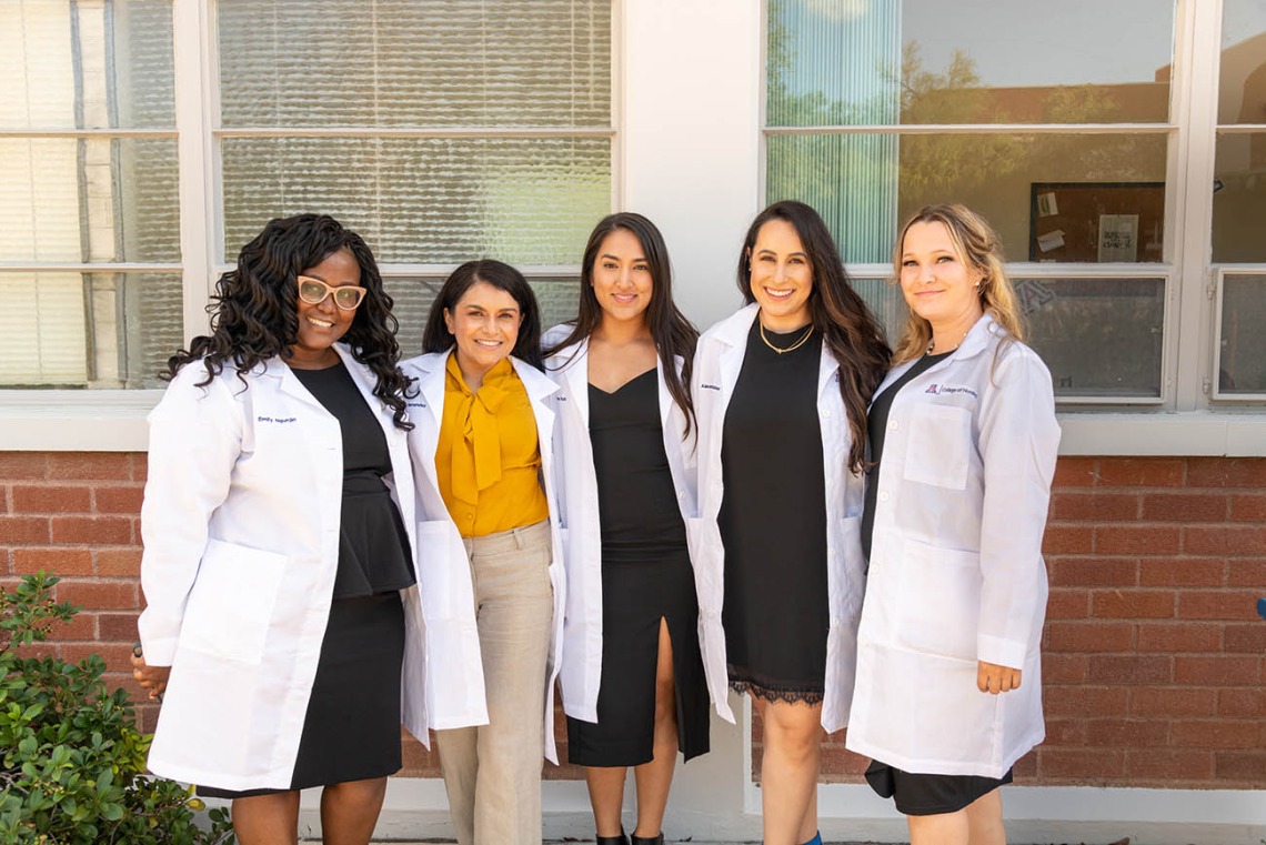Doctor of Nursing Practice students (from left) Emily Ngunjiri, Paula Maria Hernandez, Tiana Sanchez, Alexandra Robles and Kimberly Heath show off their new white coats after the ceremony. 
