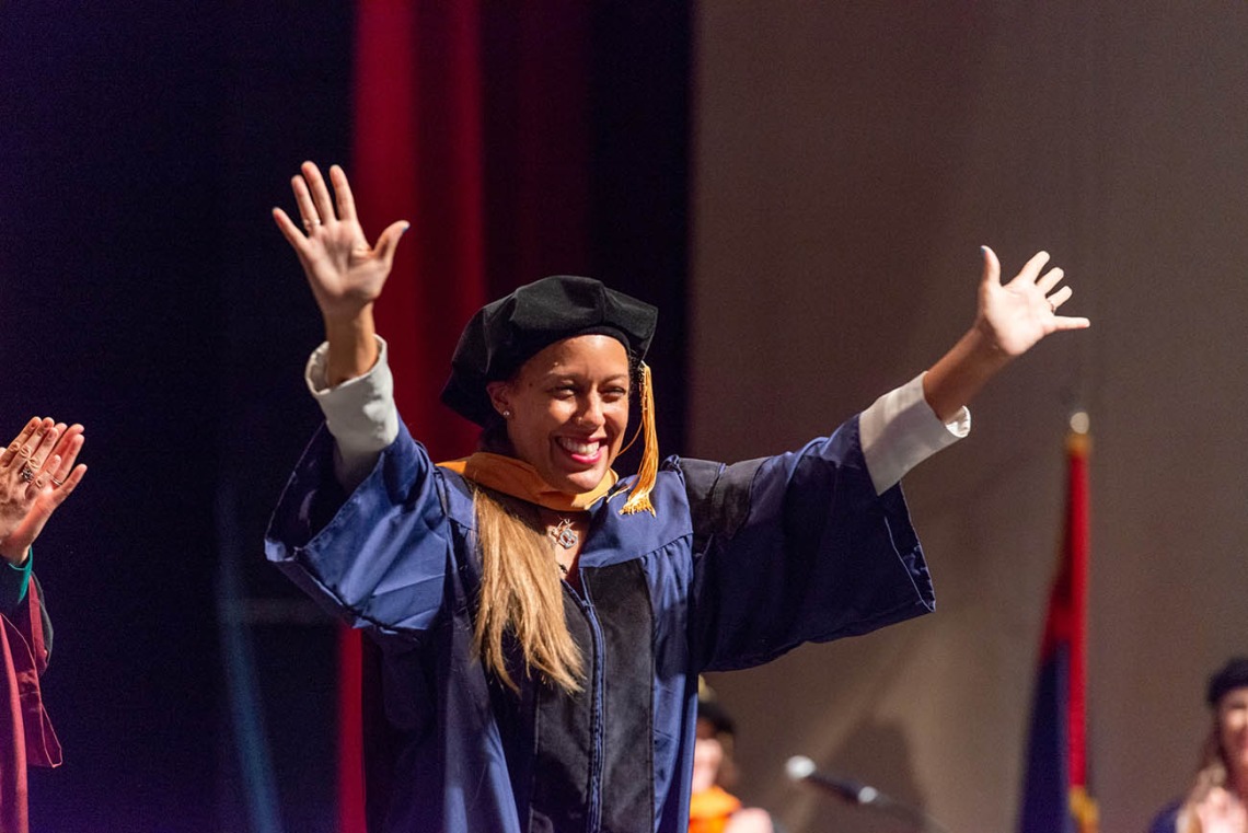 Minci Sekou Stenson, who earned a Doctor of Nursing Practice, waves to the audience after being hooded at the College of Nursing convocation at Centennial Hall in December.