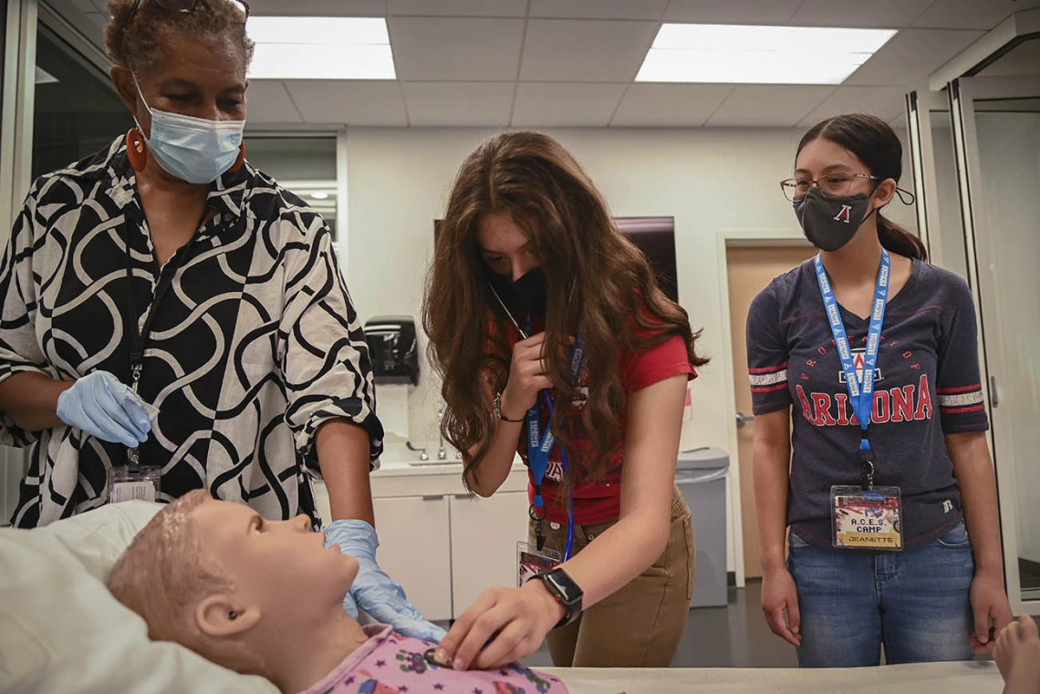 ASTEC’s Rochelle Marshall, left, helps ACES camper Ayleen Cruz find the patient simulator’s heart beat as Jeanette Mendoza watches.