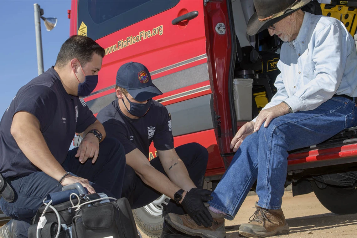 Following a telehealth consultation with Dr. Gaither, Weber helps Keller put his shoe on. (Note: This was a simulated accident scene for demonstration purposes.)