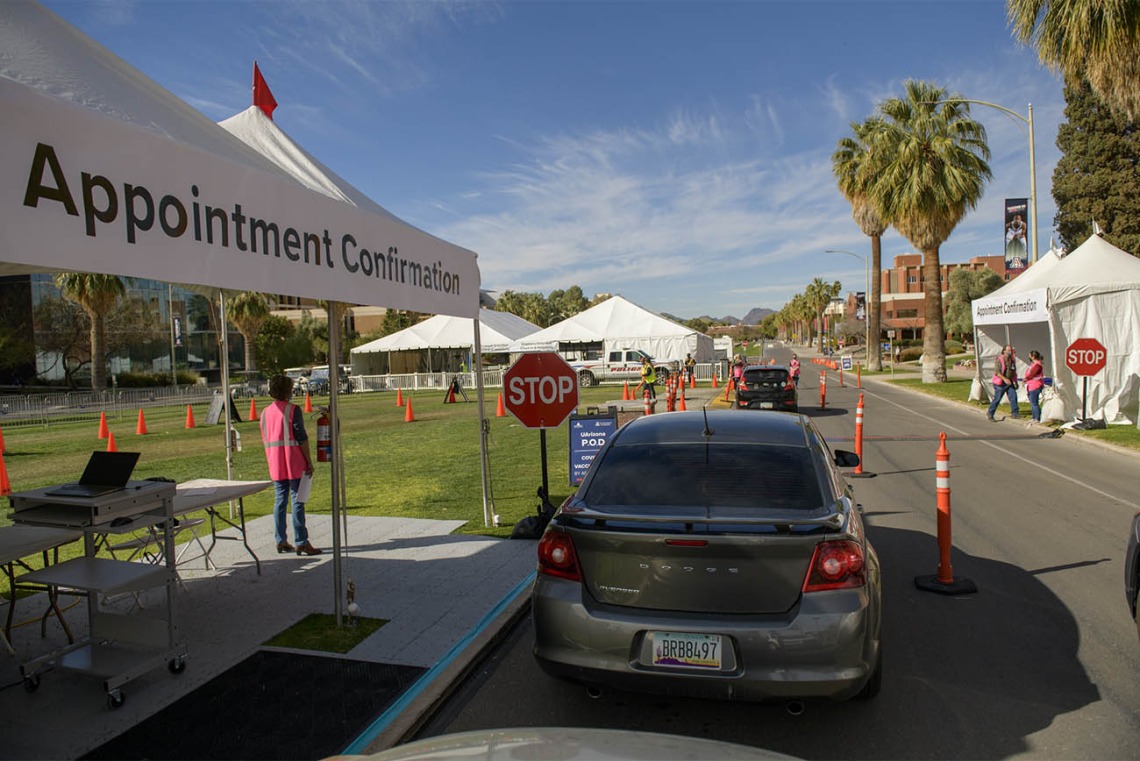 A volunteer confirms appointments as people arrive at the COVID 19 drive-through vaccine distribution site on the University of Arizona mall.