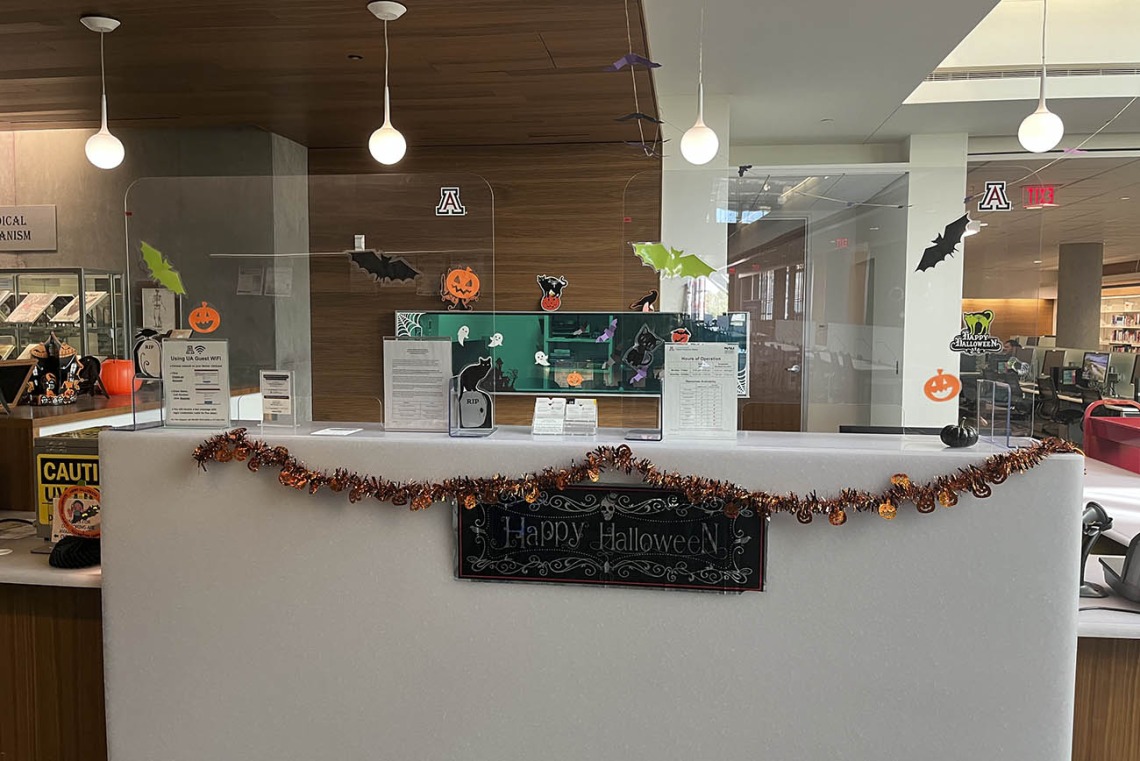 The reception desk in the Health Sciences Library is covered with various Halloween decorations. 