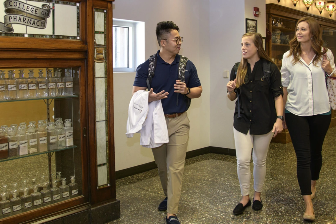 Three pharmacy students walking down a hallway.