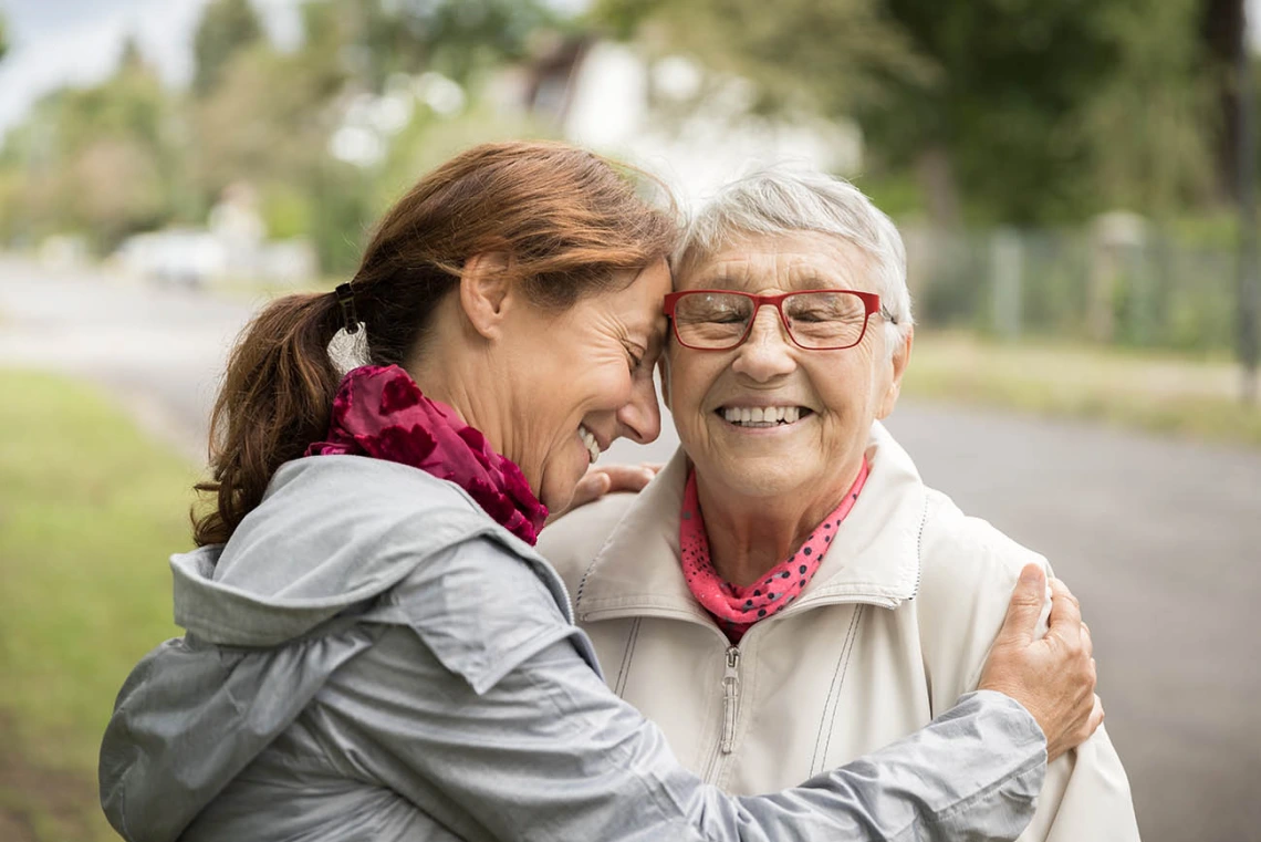 Happy senior woman and caregiver walking outdoors