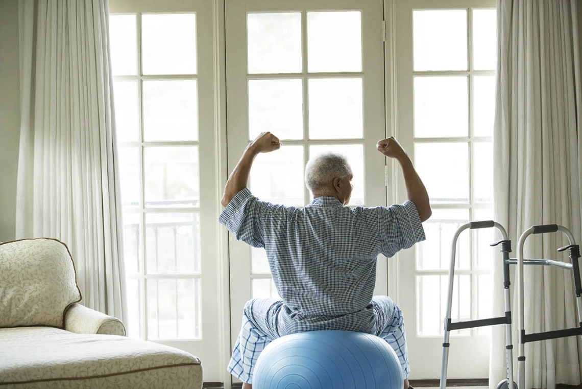 Senior African American man on fitness ball at home