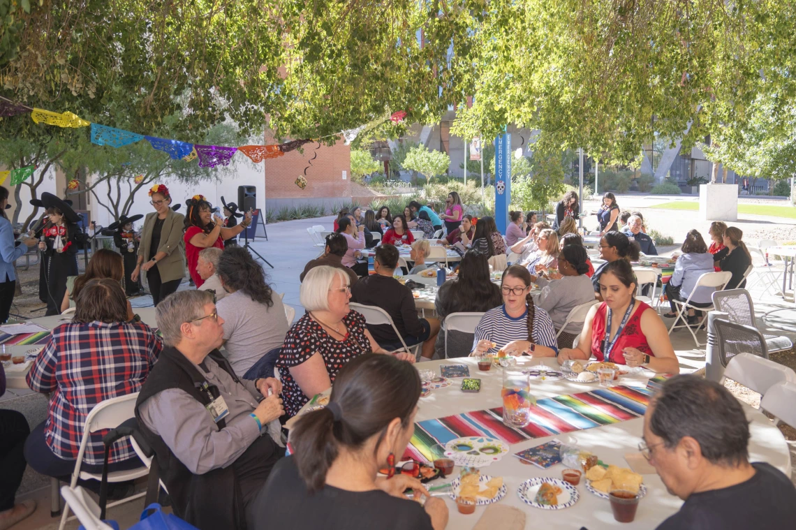 Dozens of people sitting at tables in a courtyard eating and drinking. 