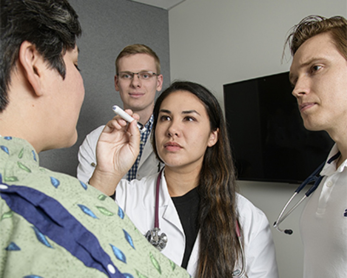 Students examine a simulated patient