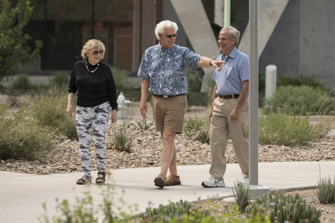 three older adults walk through the University of Arizona Health Sciences campus