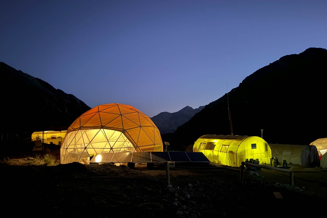 Domed camping tents glow at night.