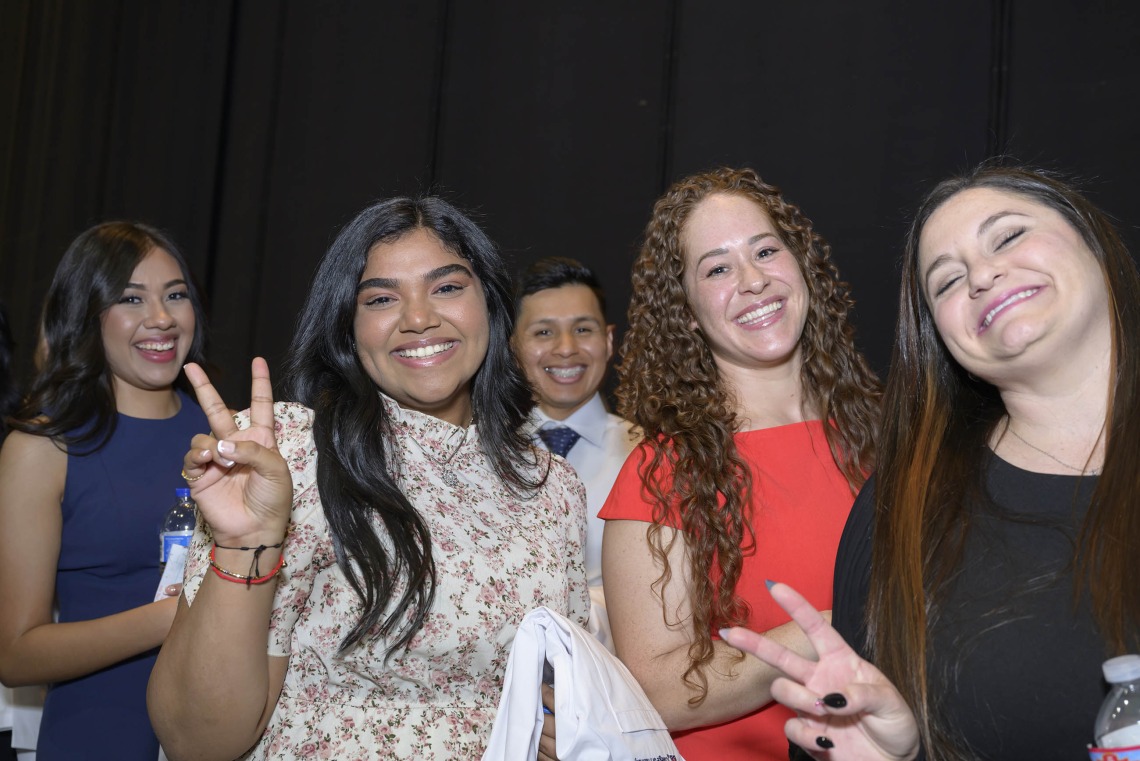 Five University of Arizona R. Ken Coit College of Pharmacy students smile as a couple of them flash peace signs.