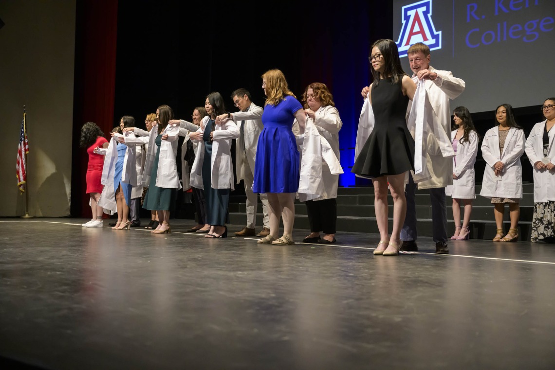 Several University of Arizona pharmacy students are presented their white coats by faculty members. 