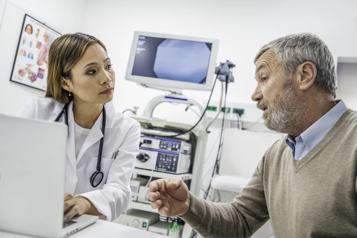 doctor with laptop talks to patient in hospital room