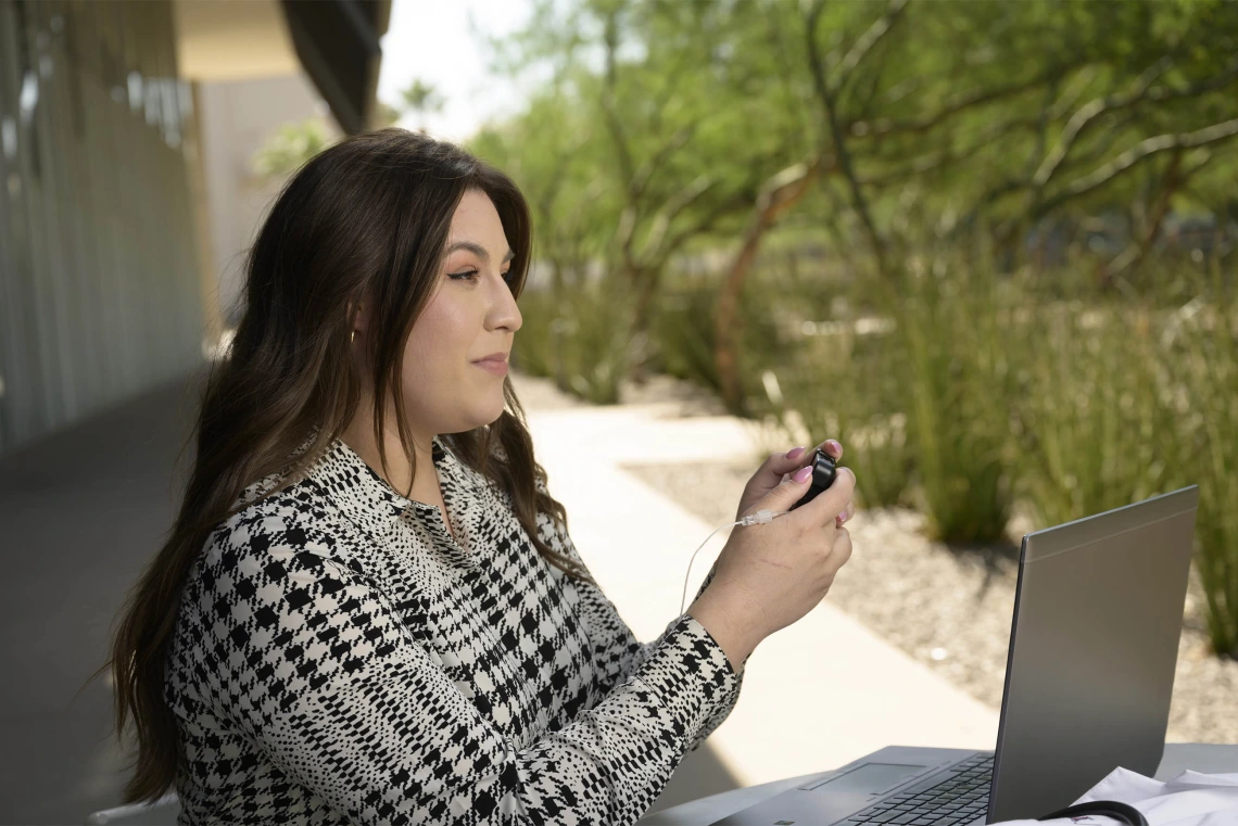 A College of Medicine – Phoenix medical student with Type 1 diabetes using a glucose monitor on herself