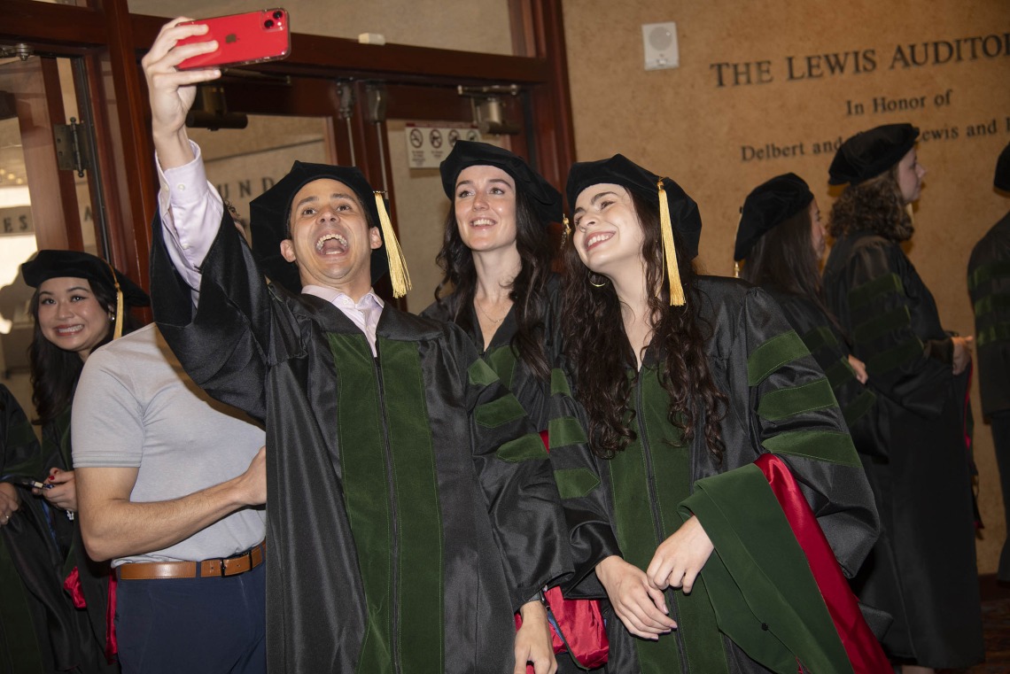 Three University of Arizona College of Medicine – Phoenix students dressed in graduation regalia take a selfie. 