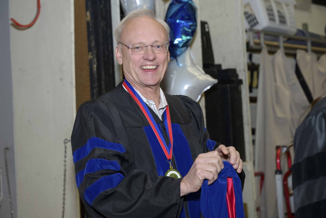 Rick Schnellmann, dean of the University of Arizona R. Ken Coit College of Pharmacy, smiles as he puts on his cap and gown. 