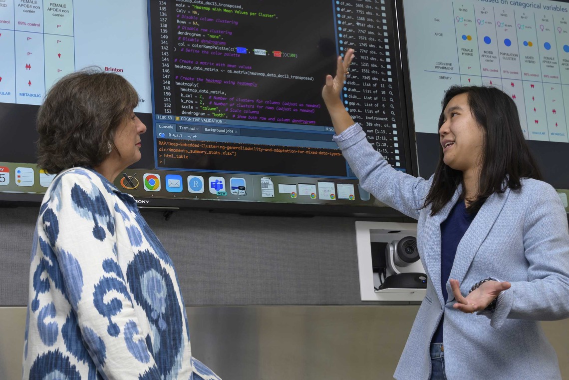 professor and doctoral student review a digital presentation on a large screen in a University of Arizona Health Sciences conference room.