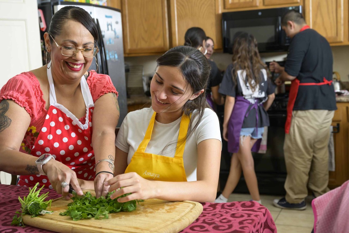 A Hispanic family in a kitchen preparing a healthy meal together 