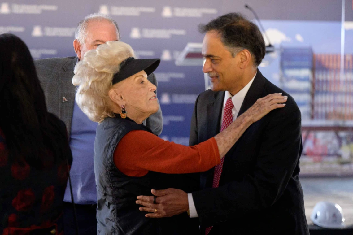 A woman puts her hand on the shoulder of a man in a suit as they talk. 