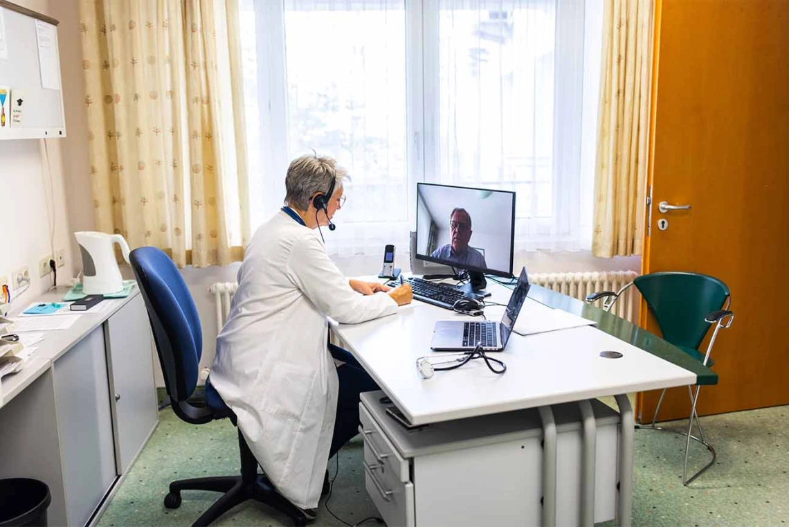 Senior medical expert having telemedicine video call with male patient at home.