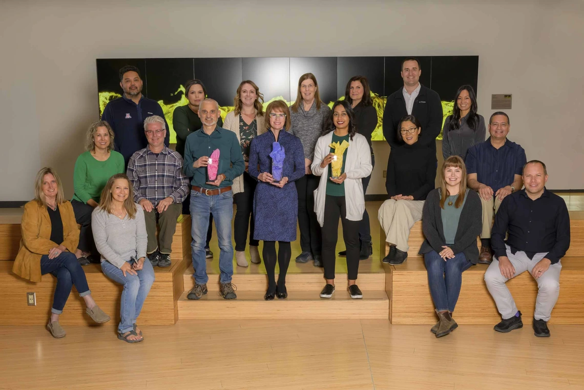 The University of Arizona Health Sciences Office of Communications staff stand together holding three PRSA awards.