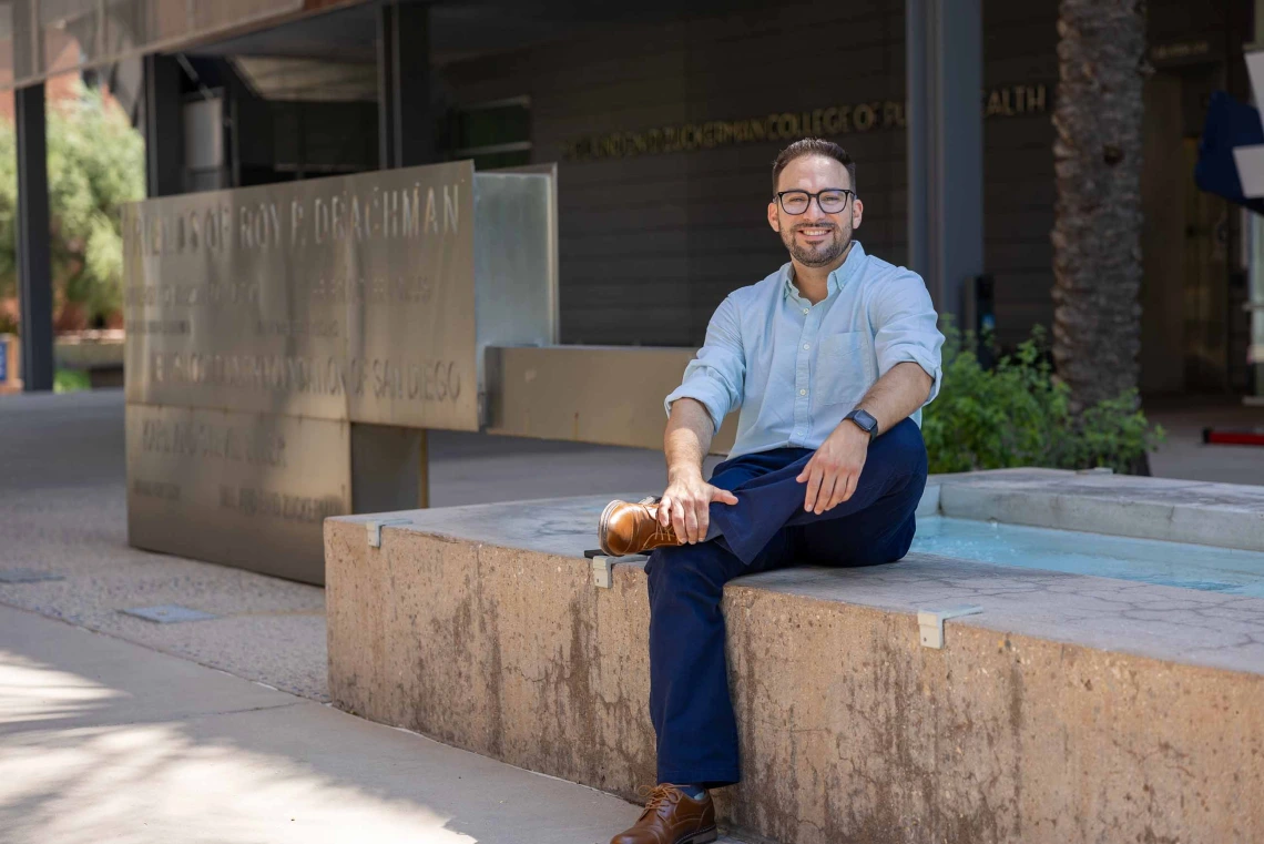 Rogelio Robles-Morales sitting next to a water fountain in front of the University of Arizona Mel and Enid Zuckerman College of Public Health