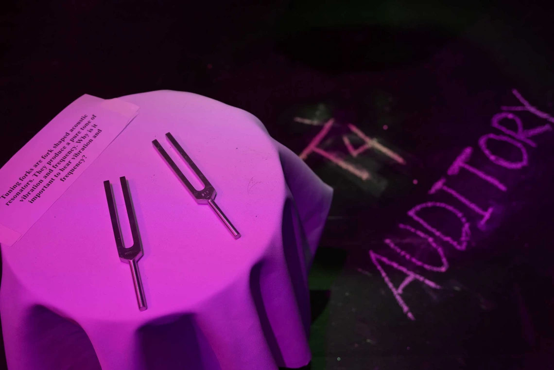 A table with two tuning forks and T4 Auditory written in chalk on a black floor