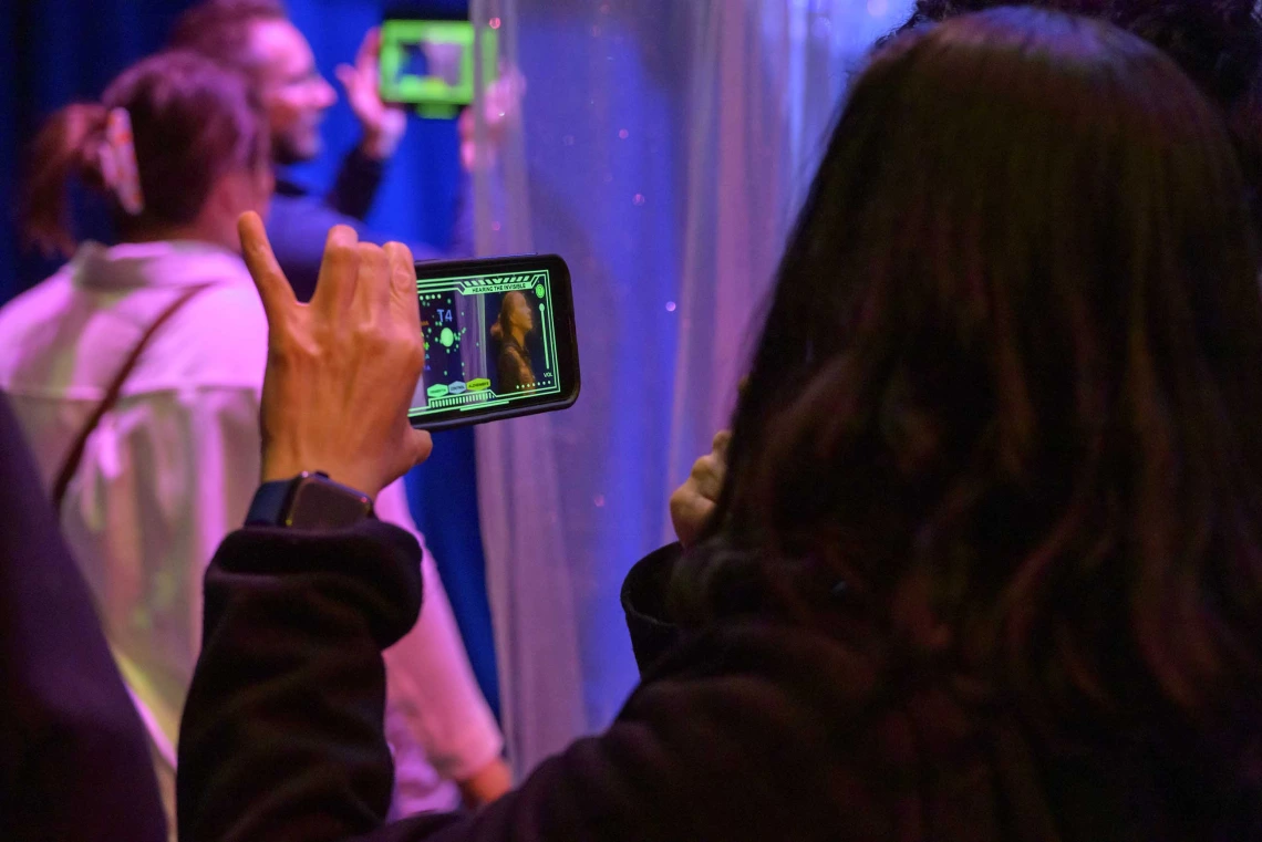 Three people, two holding up cell phones and watching the screens, at the Hearing the Invisible event at the Universit of Arizona