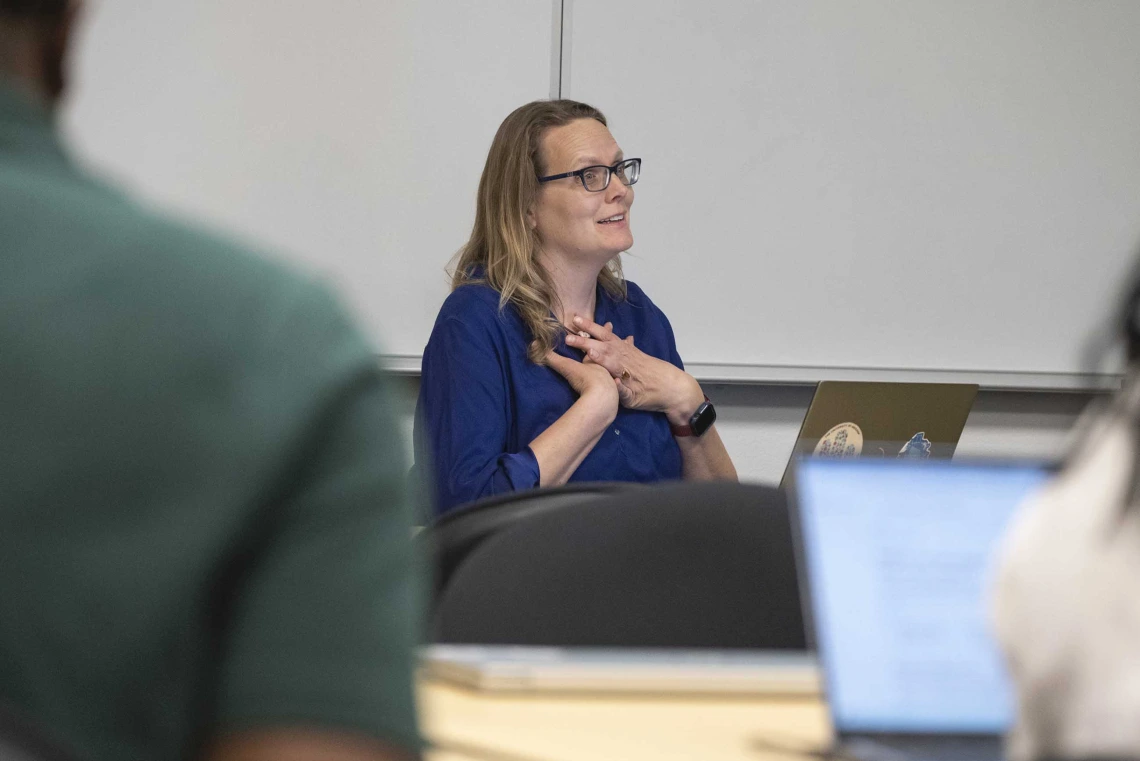 Kacey Ernst, PhD, holds her hands at her chest while talking to students.