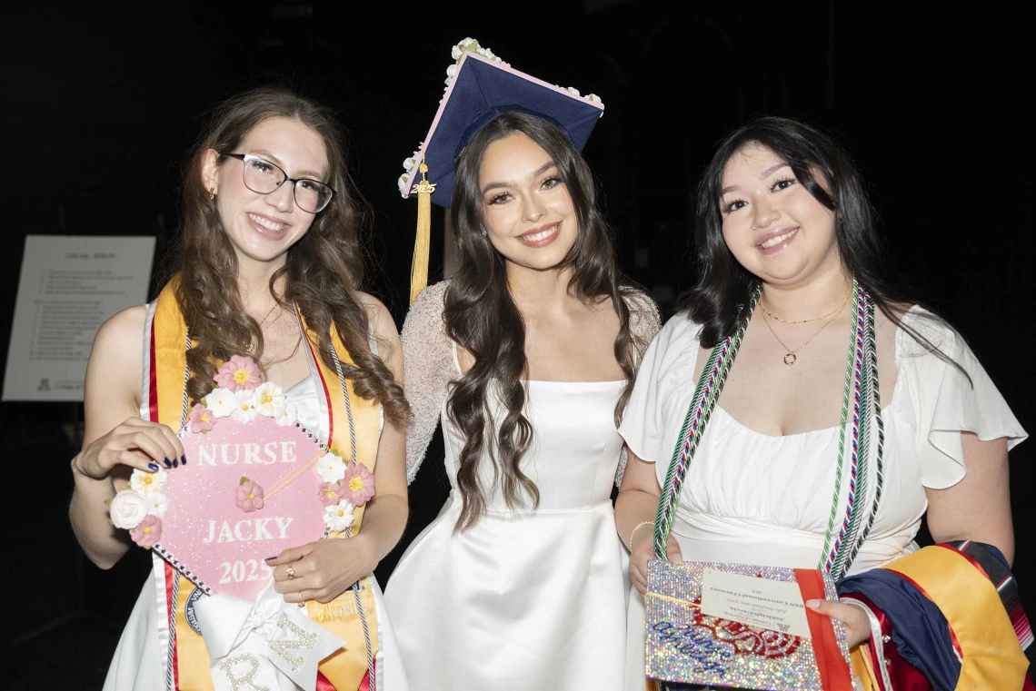 Three young women show off their graduation mortar boards as they wait backstage for the ceremony to begin. 