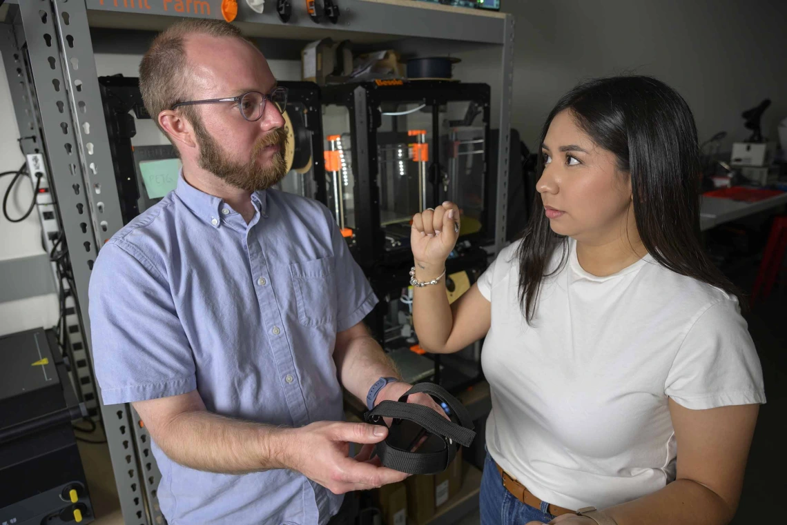 Student explains adaptive foot pedal prototype to professor in Health Sciences Design makerspace