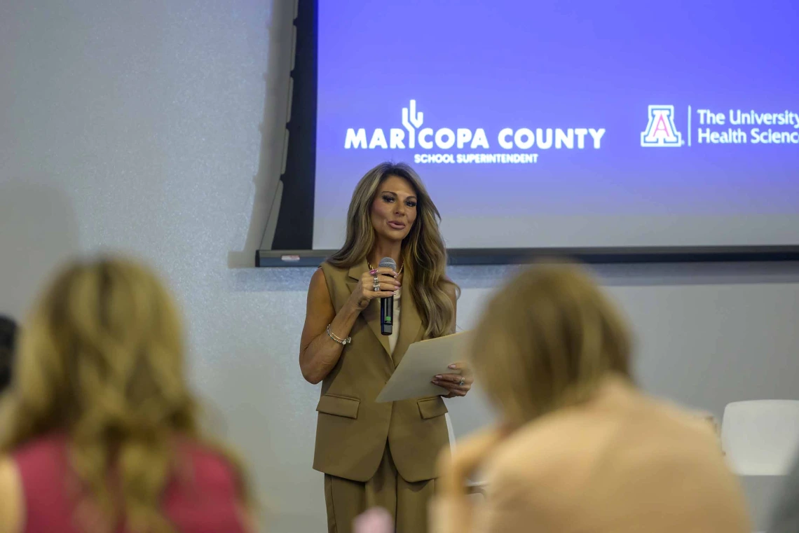 A woman stands at the front of a conference room at the Phoenix Bioscience Core, speaking into a microphone to rows of seated educators.