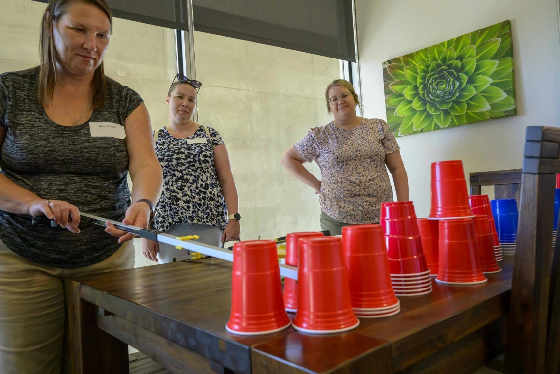 A teacher handles red cups in a hands-on therapy exercise while two other teachers watch in a classroom at the Phoenix Biomedical Campus