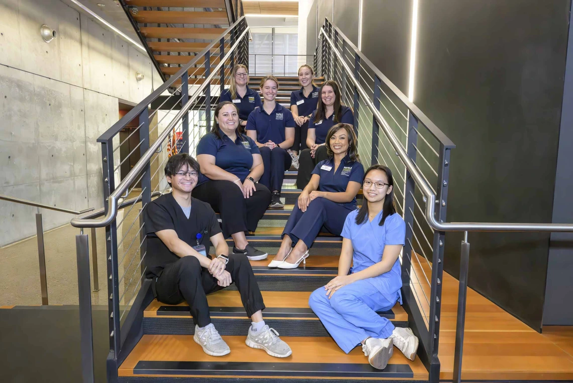 Eight students seated on a stairwell on the Phoenix Bioscience Core, arranged in rows