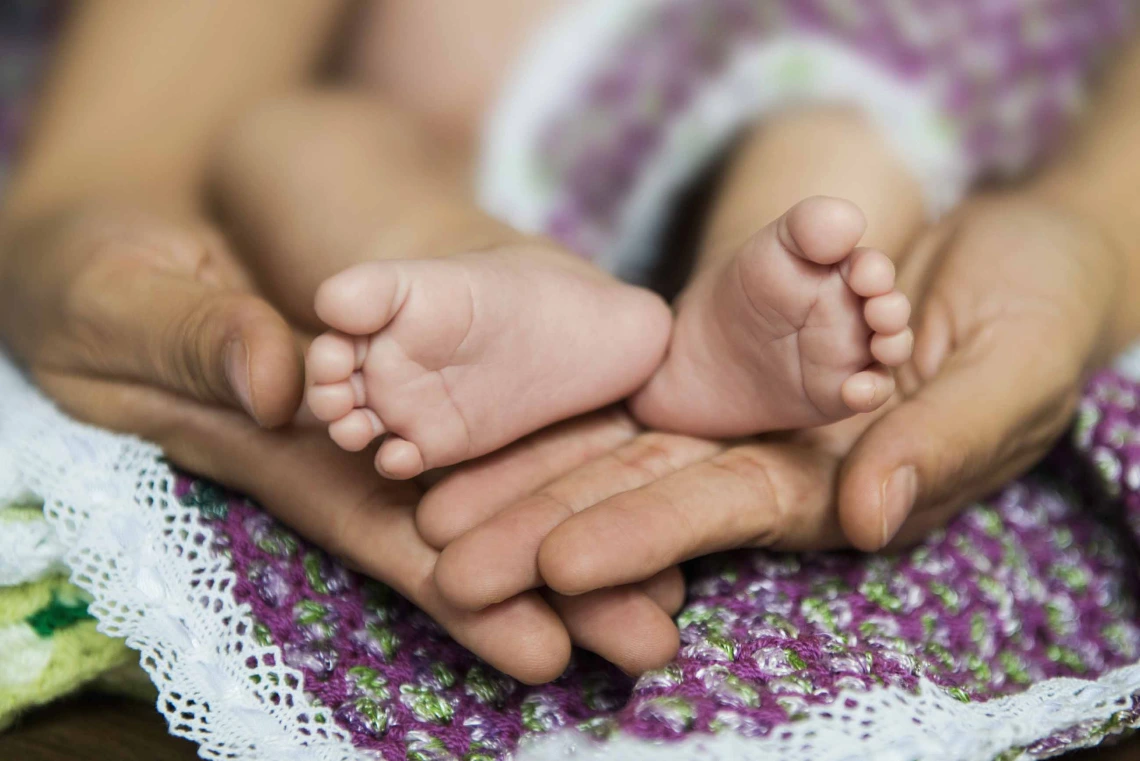 Close-up of adult hands holding baby’s feet