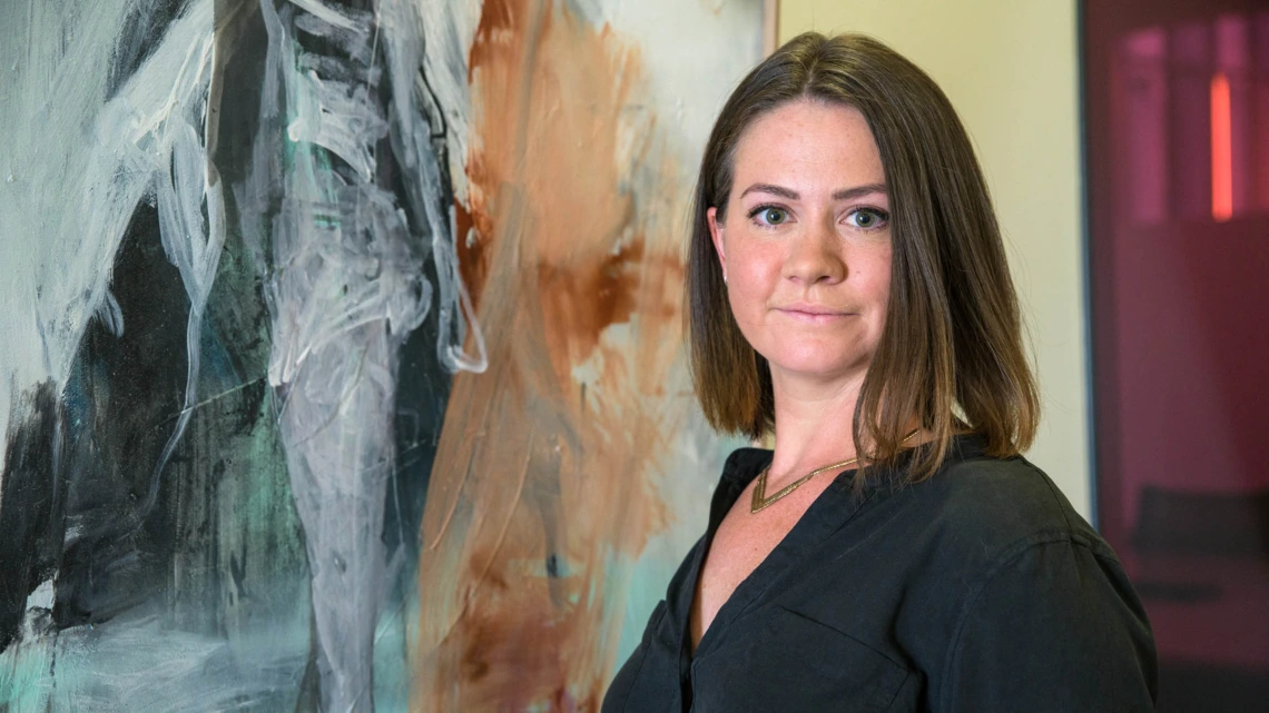 Harriet Barratt, MD, poses in front of her painting Stance, an acrylic spray paint on wood, on the fifth floor of the Health Sciences Education Building in Phoenix.